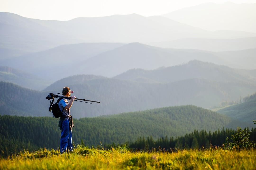 Professional photographer with tripod journey through the mountains.